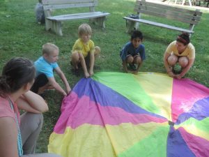 Campers work as a team preparing to lift a parachute in the air at the Newtown Friends Meetinghouse. Credit: Petra Chesner Schlatter