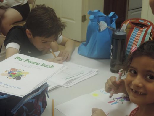 Brighton Curcio, left, draws as Leena Advani shows off her funny smile at Peace Camp, sponsored by The Peace Center. The Langhorne-based organization is celebrating its 35th anniversary. Credit: Petra Chesner Schlatter